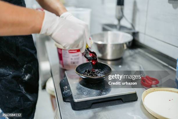 young man measuring cherry toppings in an ice cream shop - ice cream maker stock pictures, royalty-free photos & images