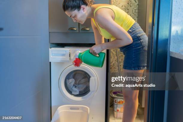 verter gel detergente líquido en lavadora - lejía fotografías e imágenes de stock