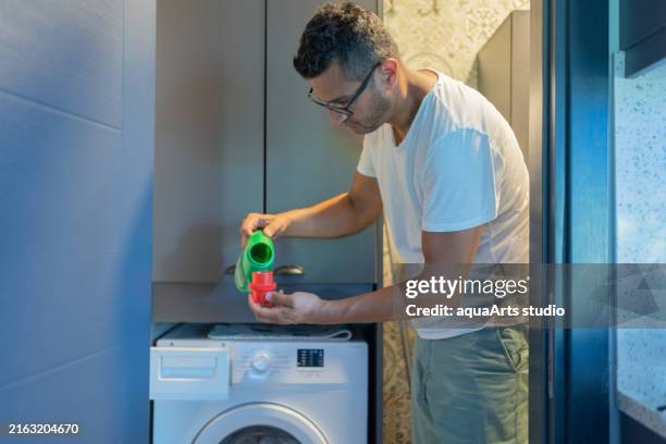 pouring liquid detergent gel in washing machine - detergente da roupa imagens e fotografias de stock
