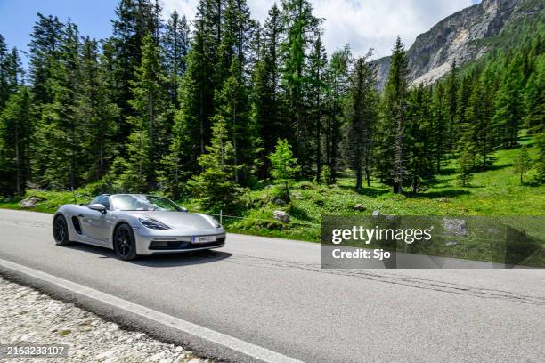 porsche 718 boxster gts 4.0 driving on a mountain road in the dolomites - luxeauto stockfoto's en -beelden