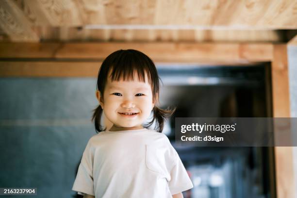 portrait of innocent little asian toddler girl making a cute face, smile as she look at the camera - weibliches baby stock-fotos und bilder