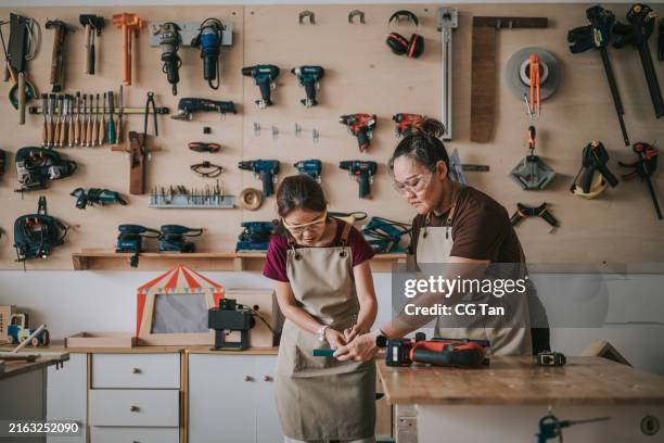 asia chinese mature female carpenter teaching female adult student wood cutting in woodshop workshop class - workbench stock pictures, royalty-free photos & images