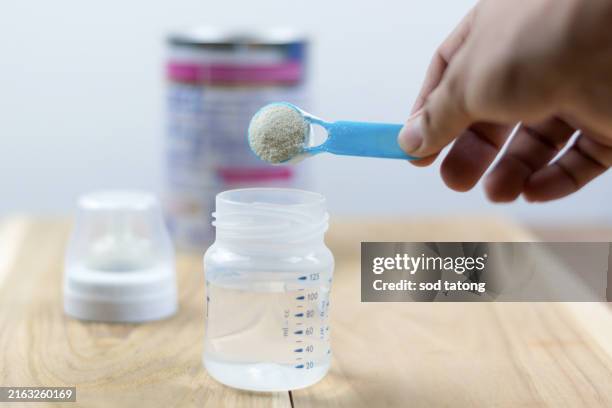 powder milk and blue spoon on light background close-up. milk powder for baby in measuring spoon on can. powdered milk with spoon for baby. baby milk formula and baby bottles - milchpulver stock-fotos und bilder