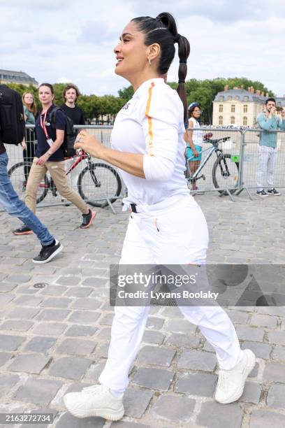 Salma Hayek runs during the Paris Olympics torch relay on July 23, 2024 in Versailles, France. Paris will host the Summer Olympics from July 26 to...