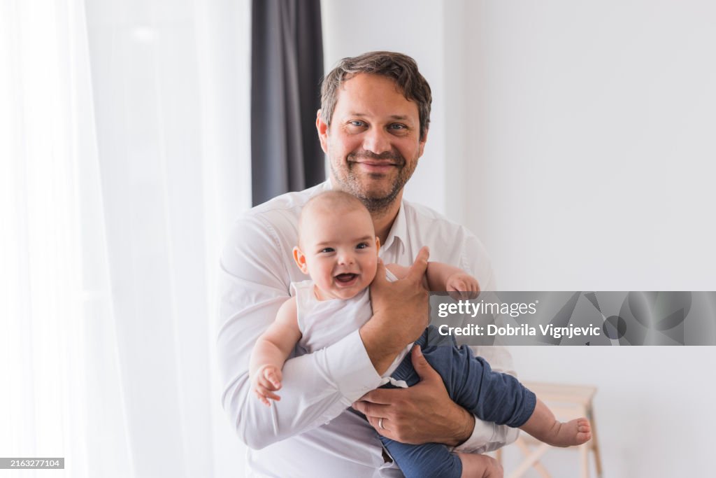 Pai orgulhoso que guarda o bebé em seus braços