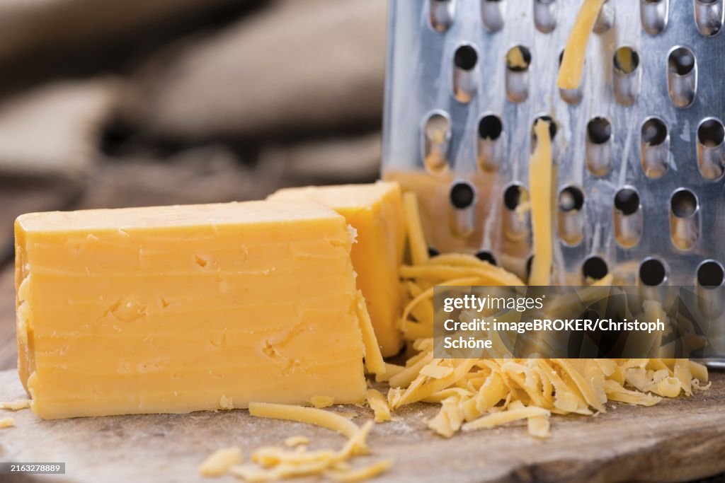 Portion of grated Cheddar Cheese on rustic wooden background