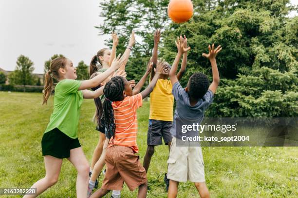 little ballers: kids showing off their basketball skillscourt conquerors: children playing basketball together - summer camp stock pictures, royalty-free photos & images