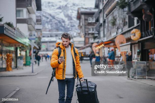 man using mobile phone to find an address of his stay in a town at switzerland - lost jacket stock pictures, royalty-free photos & images