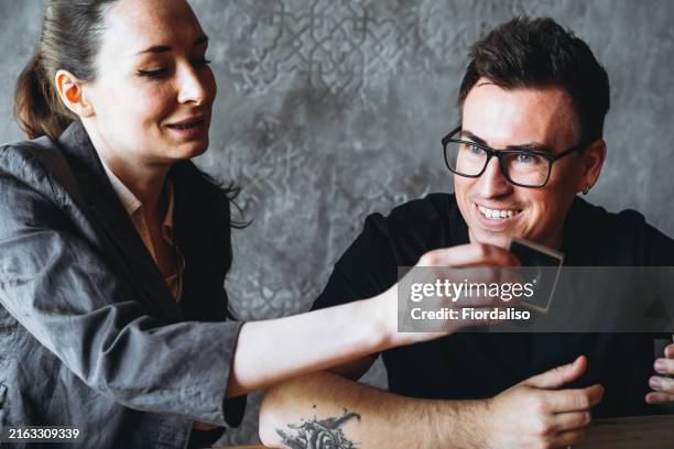 a woman and man are sitting at the table playing table games - rollenspiel stock-fotos und bilder