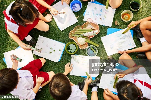children sitting in circle doing stamp painting with objects at school - green stamp stock pictures, royalty-free photos & images