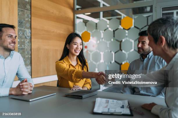 mujeres empresarias dándose la mano sobre la mesa. - reclutador fotografías e imágenes de stock