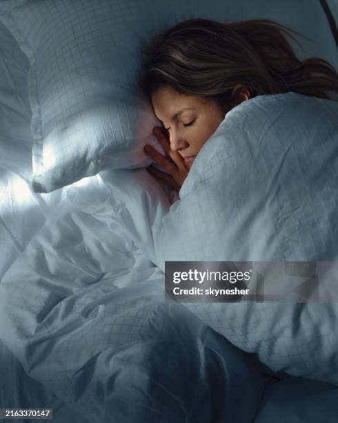 above view of relaxed woman sleeping in bed at night. - slapen stockfoto's en -beelden