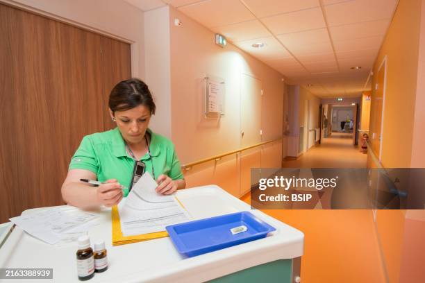 Nurse with her trolley in an empty hallway consulting a resident's file.Editorial Only.