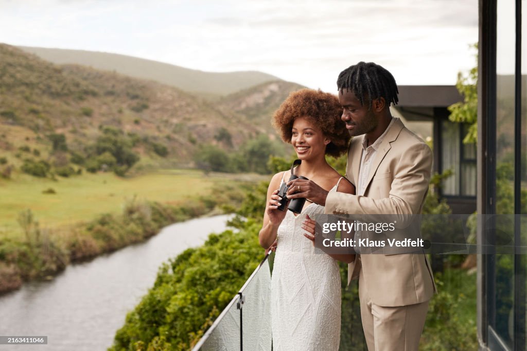 Happy bride sharing binoculars with groom
