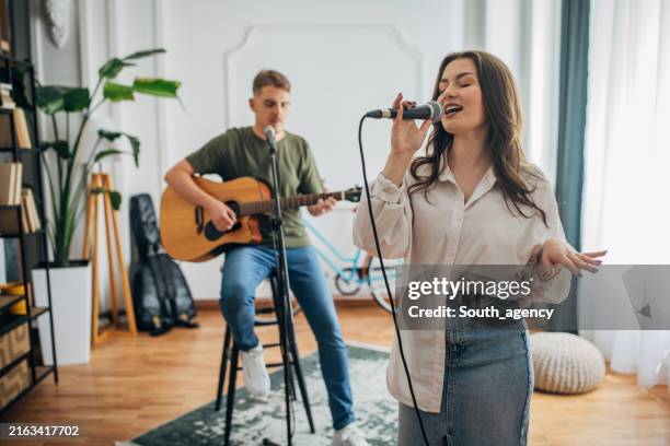 duo performing with guitar and microphone indoors, smiling - band rehearsal stock pictures, royalty-free photos & images