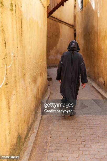 maroccan man walking in medina of fes, morocco - djellaba stock pictures, royalty-free photos & images