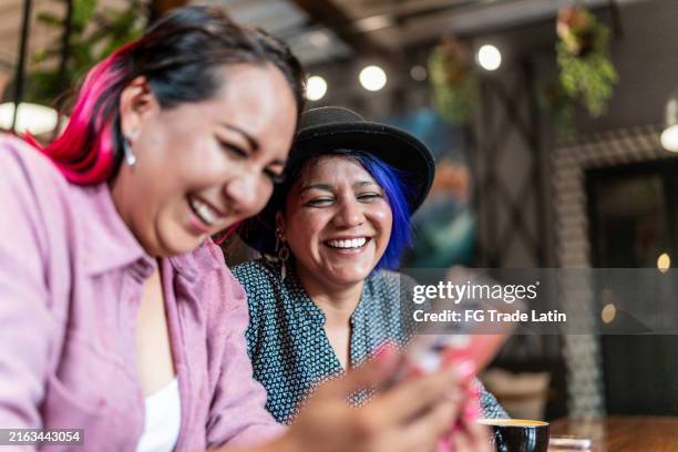 pareja de lesbianas hablando y usando el teléfono móvil en un restaurante - cabello morado fotografías e imágenes de stock