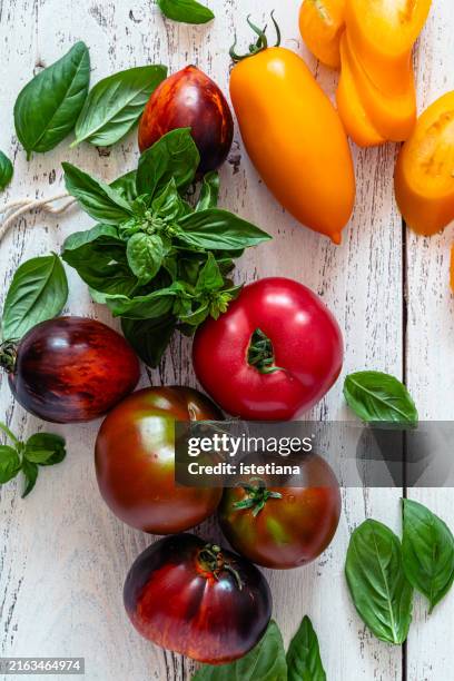 fresh summer heirloom tomatoes with green basil in wooden bowl - pflanzliche ernährung stock-fotos und bilder