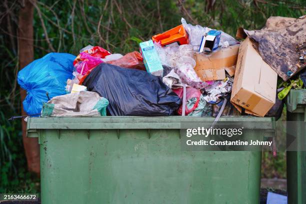 overflowing outdoor garbage bin - müllcontainer stock-fotos und bilder
