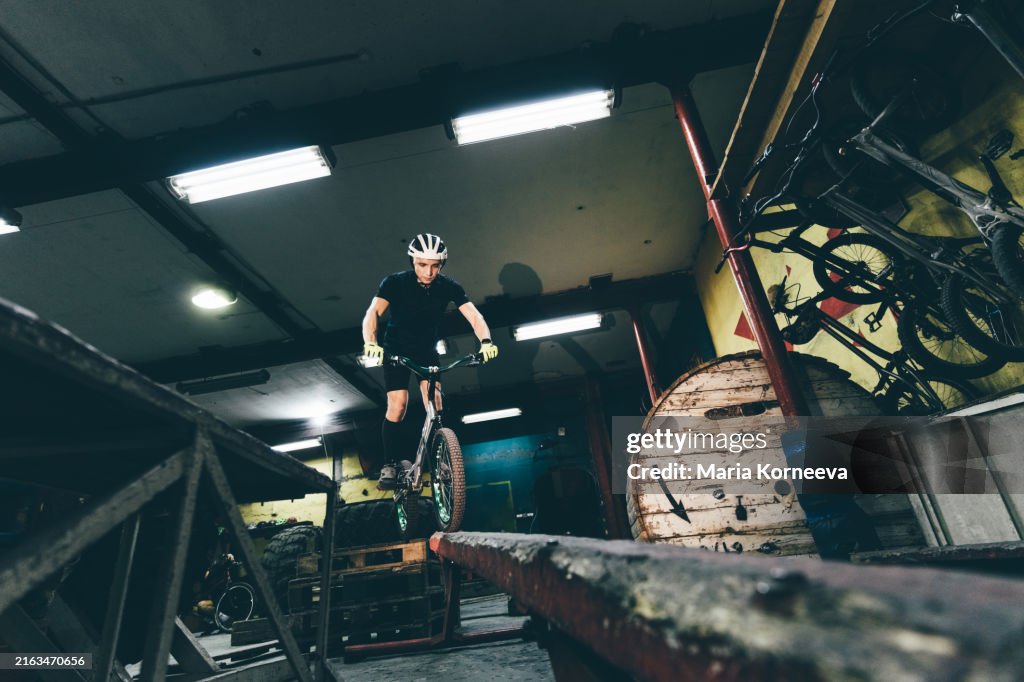 Man performing wheelies and bicycle jumps indoors.
