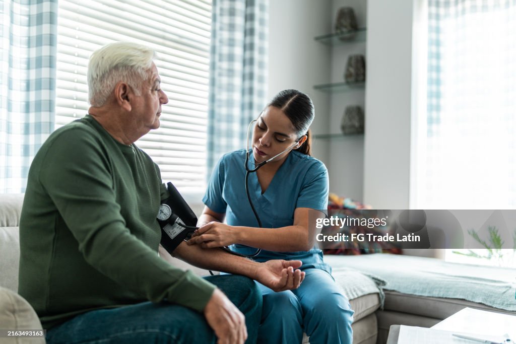 Home caregiver measuring the blood pressure of a senior man at home