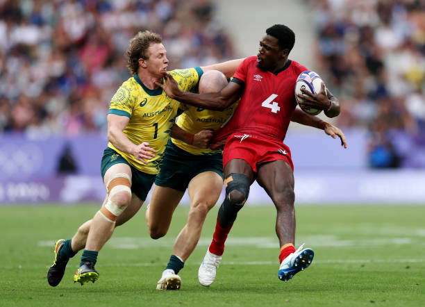Vincent Onyala of Team Kenya is tackled by Henry Hutchison and James Turner of Team Australia during the Men's Rugby Sevens Pool B Group match...