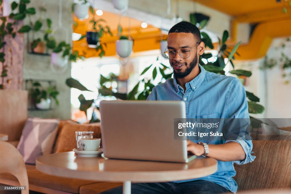 Young man sitting in coffee shop and using laptop