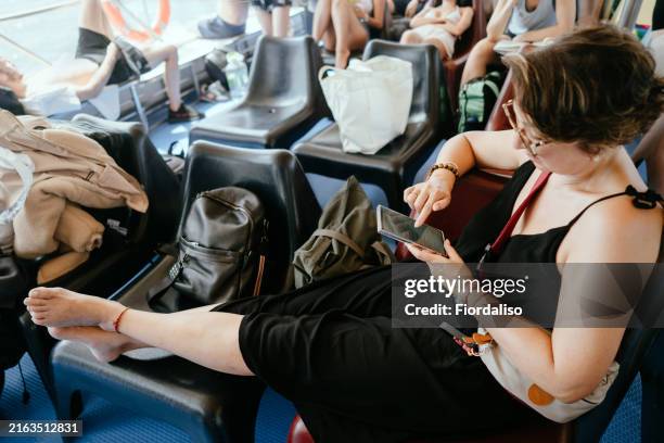 a mature woman sitting with a phone in her hands, typing a message or scrolling through a news feed on social networks. retirement age in pleasure and unity with nature, sustainability - krampfader stock-fotos und bilder