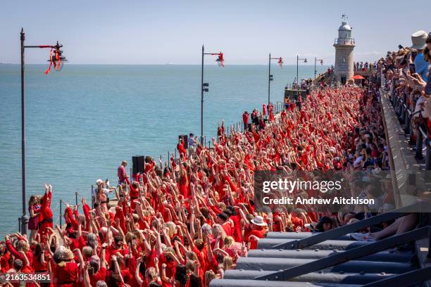 Hundreds of Kate Bush fans came together wearing red floaty dresses on Folkestone's Harbour Arm to dance to her most iconic song, Wuthering Heights...