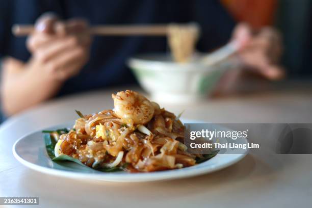close up shot of a plate of char koay teow served on a banana leaf in a local hawker stall in penang - wok stockfoto's en -beelden
