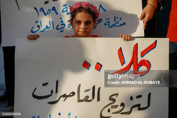 Girl holds a placard as activists demonstrate against female child marriages, in Tahrir Square in central Baghdad on July 28 amid parliamentary...