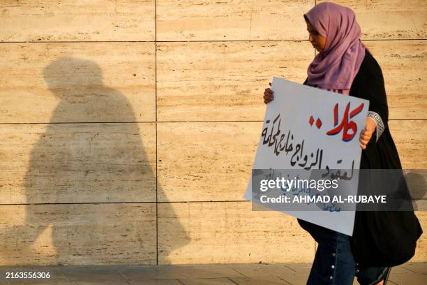 Woman walks holding a placard as activists demonstrate against female child marriages, in Tahrir Square in central Baghdad on July 28 amid...