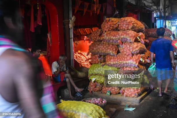 People are passing next to potato sacks at a wholesale vegetable market in Kolkata, India, on July 28, 2024.