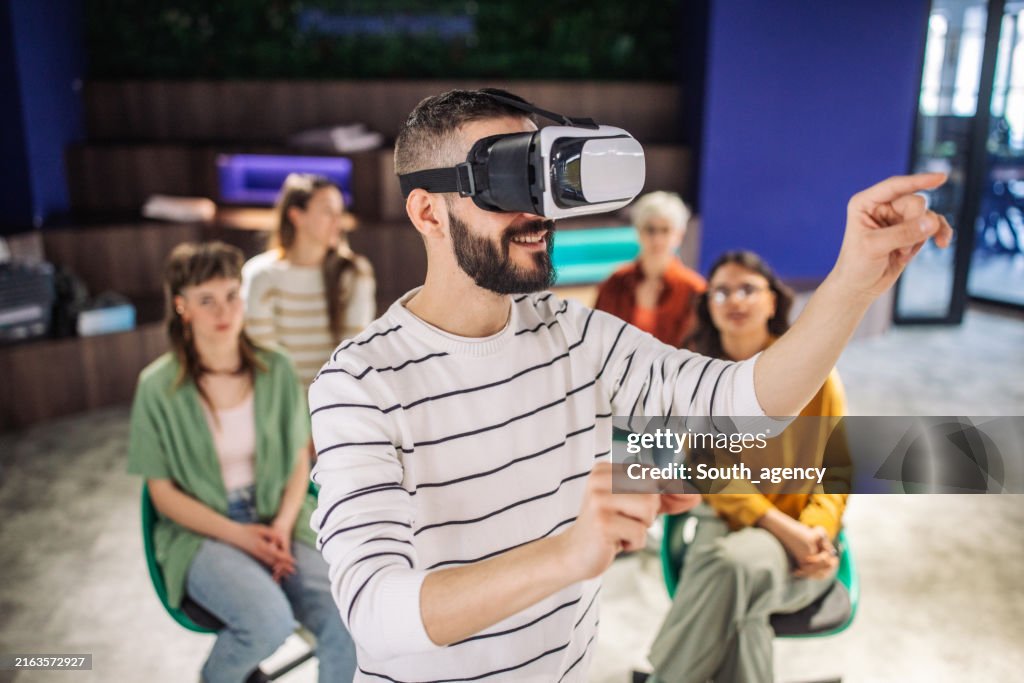 Person engaged with virtual reality as others observe.