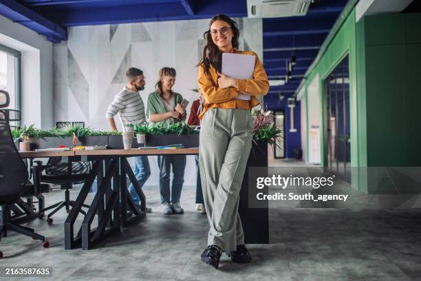 woman standing by desk in open office environment - atmosphere stock pictures, royalty-free photos & images