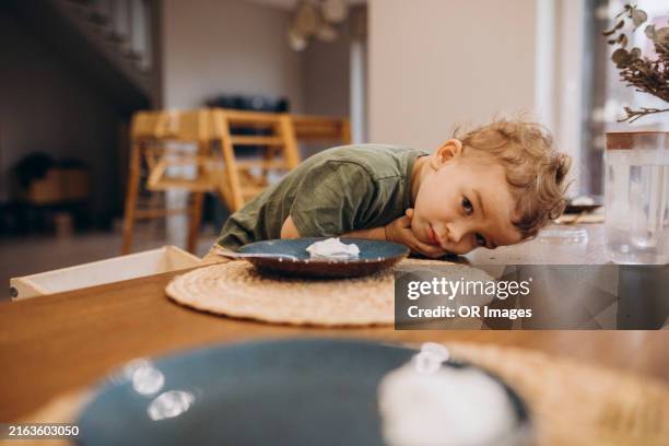 boy leaning on dining table at home - child empty plate stock pictures, royalty-free photos & images