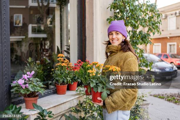 portrait of a young woman choosing plant vase in a flower shop - tuincentrum stockfoto's en -beelden