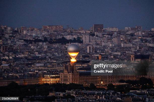 An aerial view of the Olympic cauldron lit with the Olympic flame as it flies above Paris while attached to a balloon, seen from the Eiffel Tower, on...