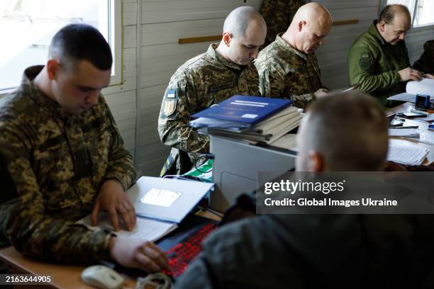 Servicemen talk with volunteers at the conscription point during sign a contract with the Ukrainian army on March 26, 2024 in Unspecified, Ukraine....