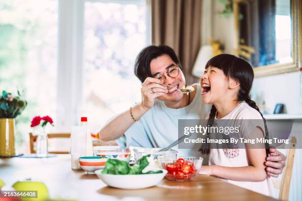 young asian father and daughter sharing a fun cooking moment at home - day in the life series stock pictures, royalty-free photos & images