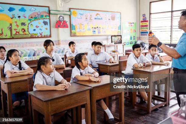 teacher giving science lesson to students in elementary school classroom - thailand school uniform stock pictures, royalty-free photos & images