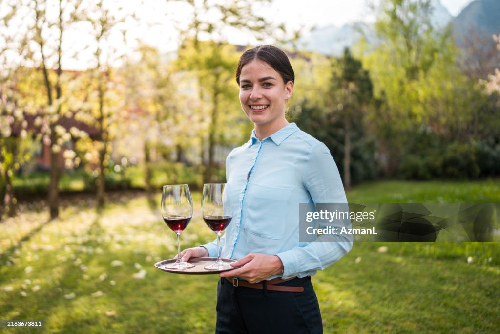Elegante Kellnerin, die Wein im Freien serviert