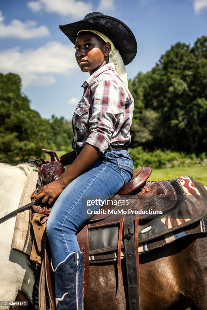 Young woman riding horse in pasture