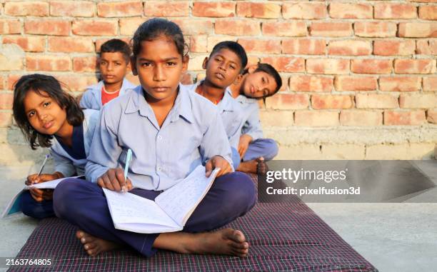 rural children sitting in a row at home and studying together - ontwikkelingslanden stockfoto's en -beelden