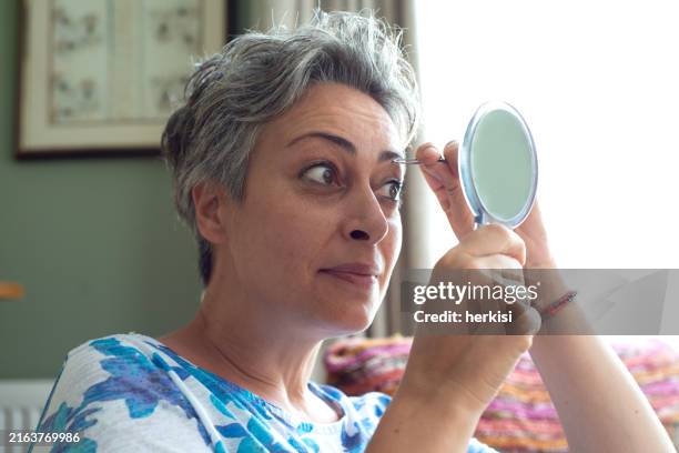 woman plucking eyebrows at home - tweezing eyebrows stock pictures, royalty-free photos & images