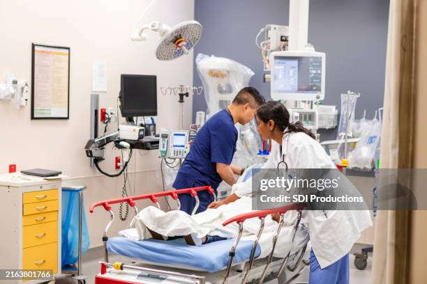 el médico y la enfermera de la sala de emergencias preparan a la mujer inconsciente para el examen - urgencia fotografías e imágenes de stock
