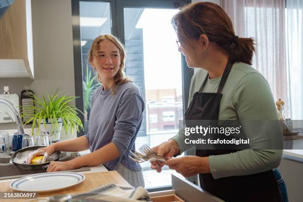 teenage girl washing dishes with her mother - poetshulp stockfoto's en -beelden