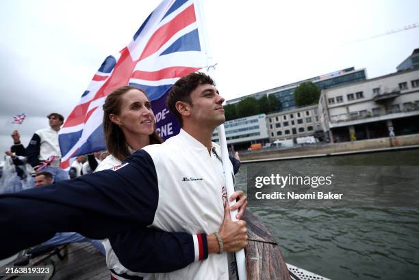 Thomas Daley, Helen Glover, Flagbearers of Team Great Britain, gesture on a boat while holding the national flag on the River Seine during the...