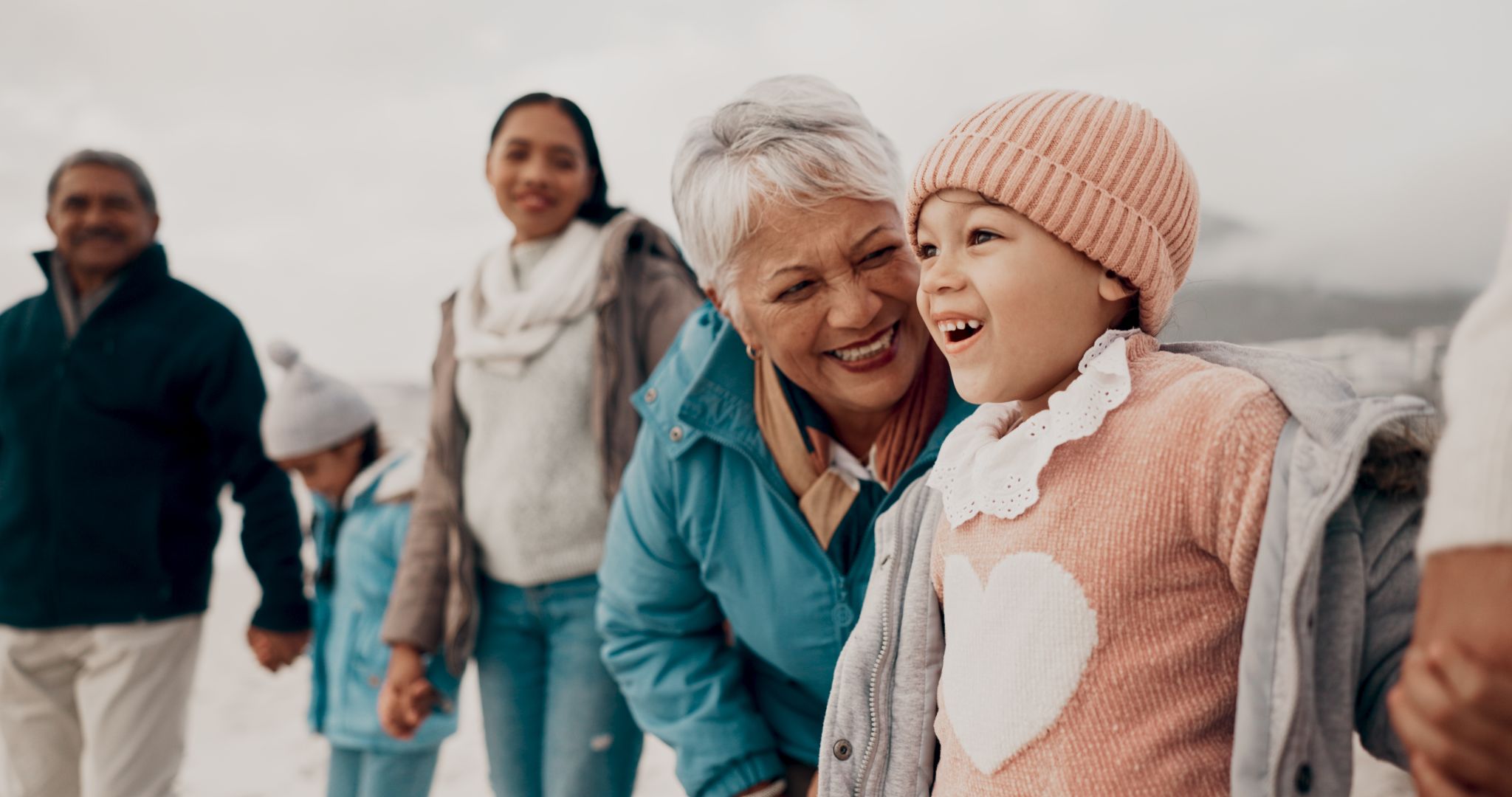Grandmother, girl and family at beach with smile, holding hands or outdoor with care, walk and vacation. People, generations and kids with laugh for funny conversation with bonding on winter holiday Grandmother, girl and family at beach with smile, holding hands or outdoor with care, walk and vacation. People, generations and kids with laugh for funny conversation with bonding on winter holiday