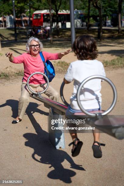 grandmother having fun on seesaw with grandson in park - seesaw stock pictures, royalty-free photos & images